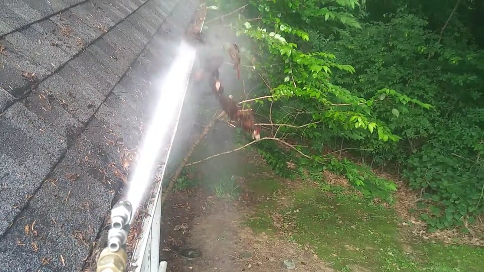 Water rinsing debris from a gutter during Deluxe Gutter Cleaning