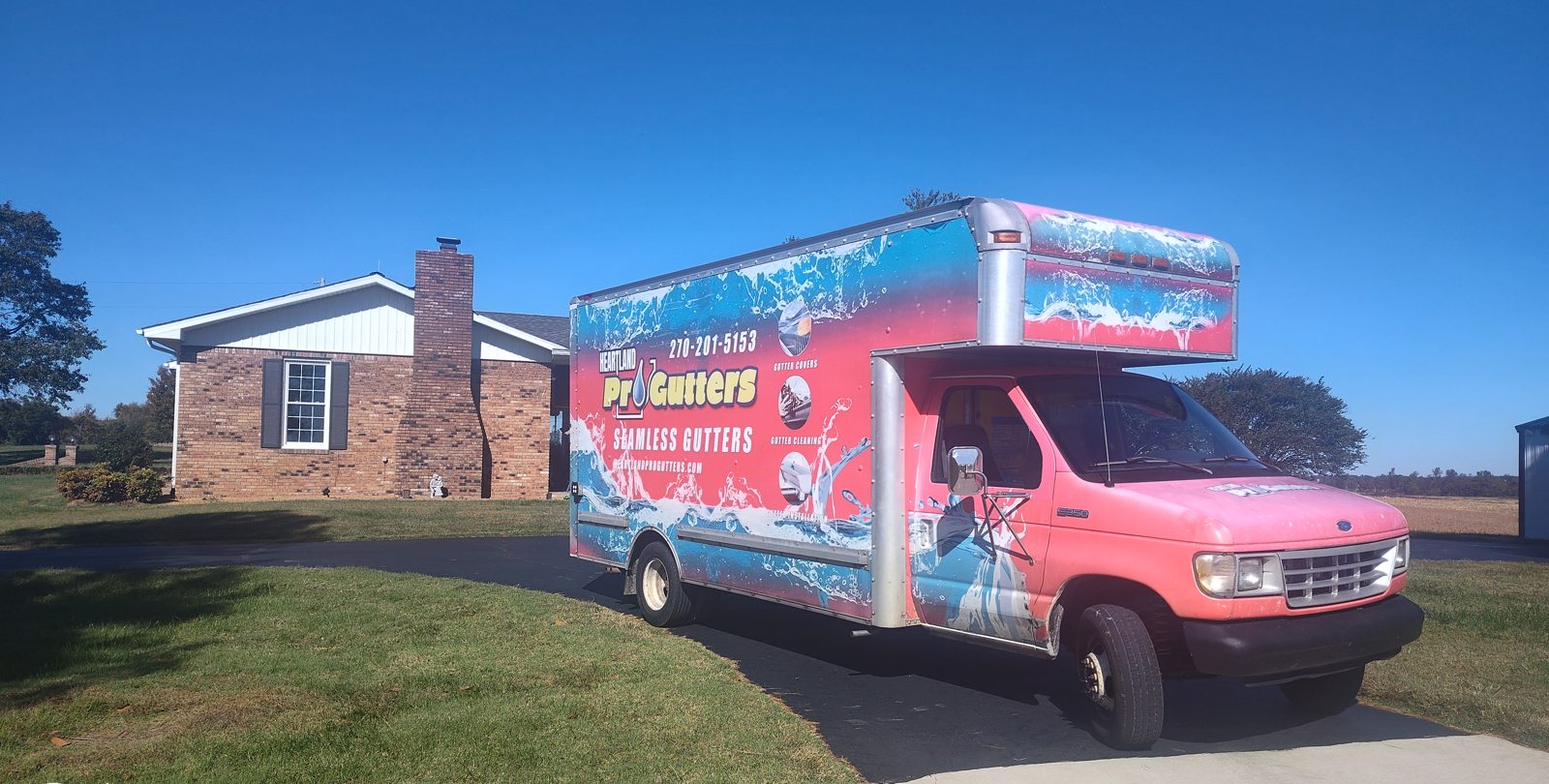 Heartland ProGutters truck parked at a brick ranch for gutter cleaning in Kirbyton near Bardwell, KY